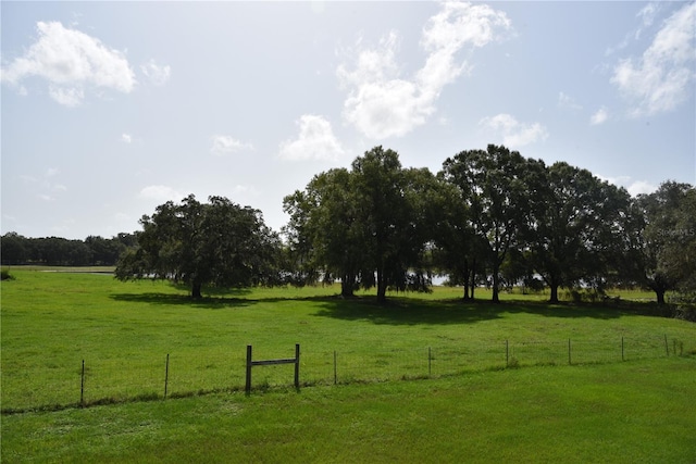view of home's community with a lawn, fence, and a rural view
