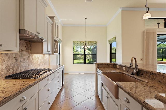 kitchen featuring tasteful backsplash, a sink, stainless steel gas stovetop, baseboards, and under cabinet range hood