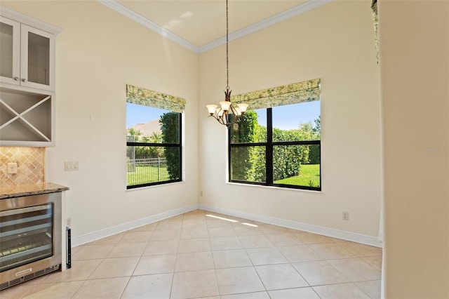 unfurnished dining area featuring a chandelier, light tile patterned flooring, crown molding, baseboards, and beverage cooler