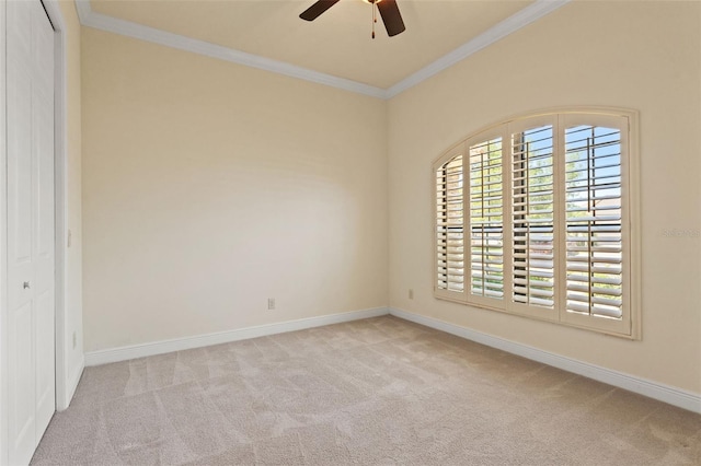 spare room featuring ornamental molding, carpet flooring, ceiling fan, and baseboards