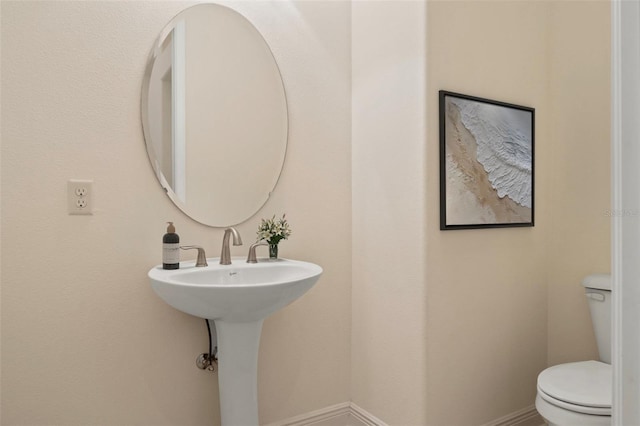 half bathroom featuring toilet and baseboards
