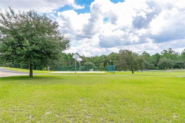 view of home's community featuring a yard, community basketball court, and fence