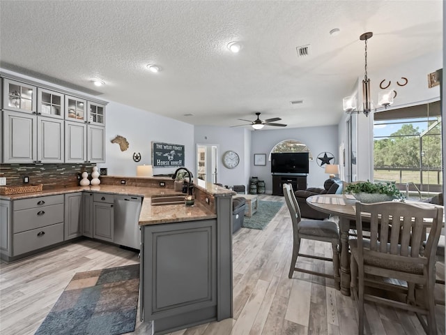 4658 W Hacienda Dr, Beverly Hills, FL 34465 - kitchen with a peninsula, stainless steel dishwasher, a sink, light wood-style floors, and gray cabinets