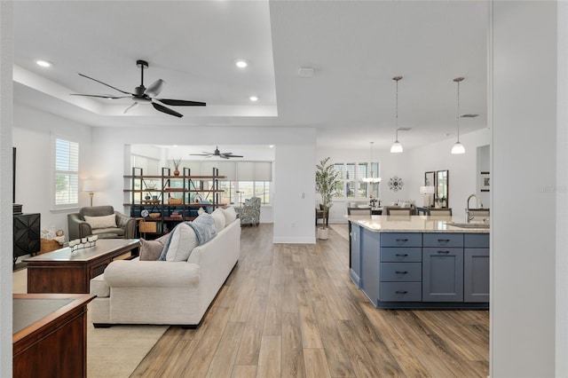 9764 SW 81st Ln, Ocala, FL 34481 - living room with a ceiling fan, light wood-style flooring, a raised ceiling, baseboards, and recessed lighting