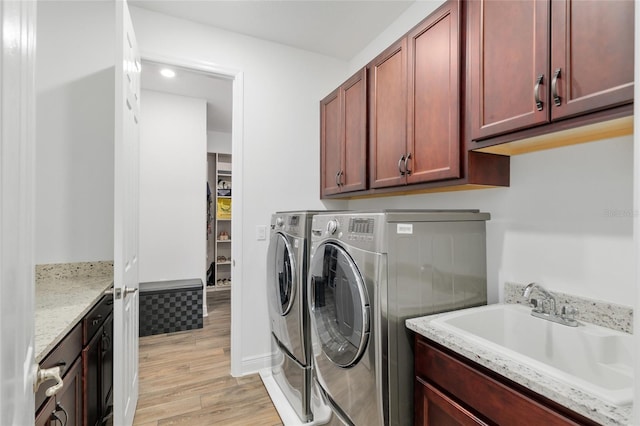 9764 SW 81st Ln, Ocala, FL 34481 - laundry area featuring cabinet space, light wood-style flooring, washing machine and clothes dryer, and a sink