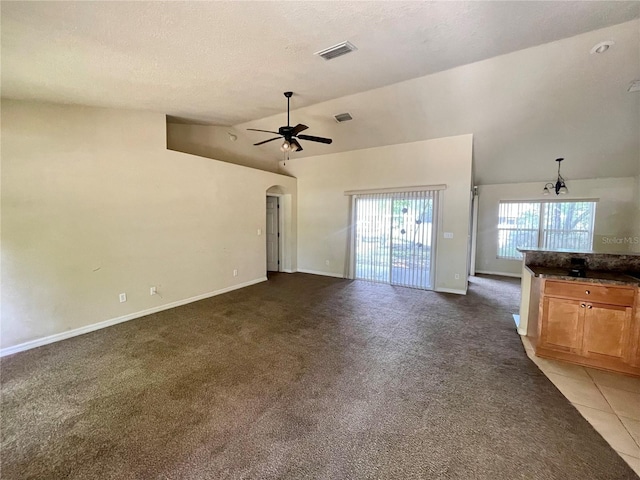 unfurnished living room featuring vaulted ceiling, a ceiling fan, arched walkways, baseboards, and carpet flooring