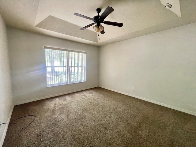 carpeted empty room featuring baseboards, a ceiling fan, a tray ceiling, and a textured ceiling