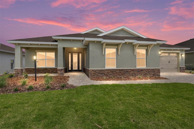 view of front facade featuring stucco siding, an attached garage, stone siding, and a front yard