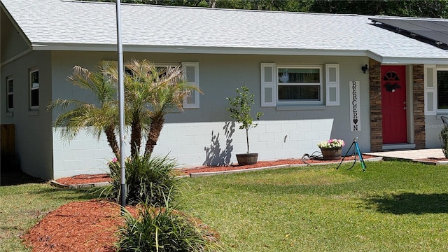 view of front of property featuring a shingled roof, a front lawn, and solar panels