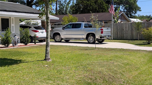 view of yard with fence, a carport, and concrete driveway