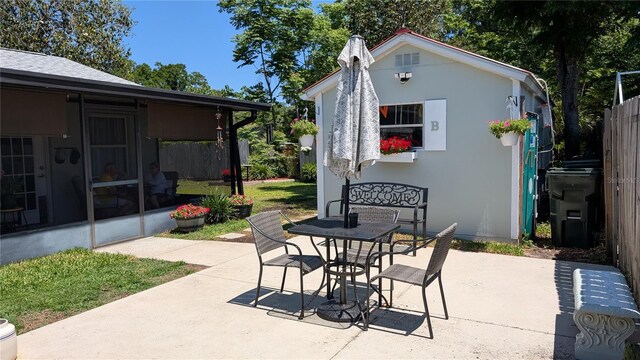 view of patio / terrace featuring a sunroom, outdoor dining area, and fence