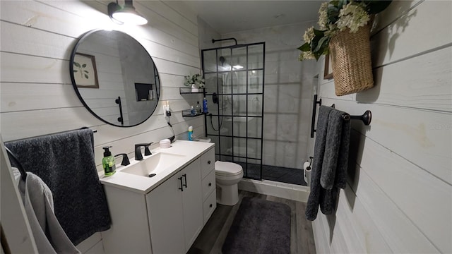 full bath with a tile shower, toilet, vanity, and wood finished floors