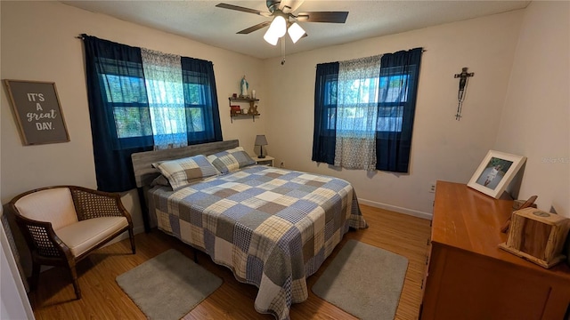 bedroom featuring wood finished floors, baseboards, and multiple windows