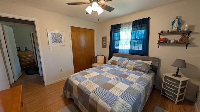 bedroom featuring ceiling fan, baseboards, wood finished floors, and a closet