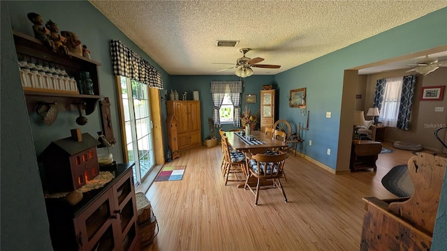 dining area with ceiling fan, a textured ceiling, visible vents, and light wood-type flooring