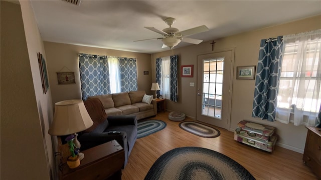 living room with visible vents, baseboards, wood finished floors, and ceiling fan