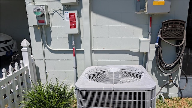 exterior details with electric meter, concrete block siding, and cooling unit