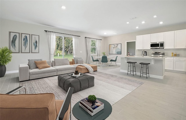 living area with recessed lighting, light wood-style flooring, visible vents, and baseboards