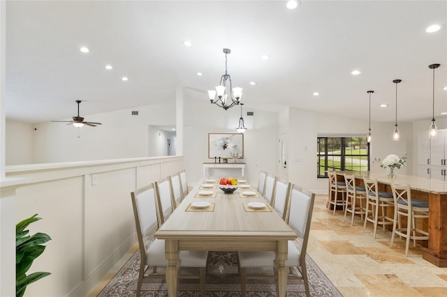 dining space with vaulted ceiling, recessed lighting, light stone finish floors, a ceiling fan, and a chandelier
