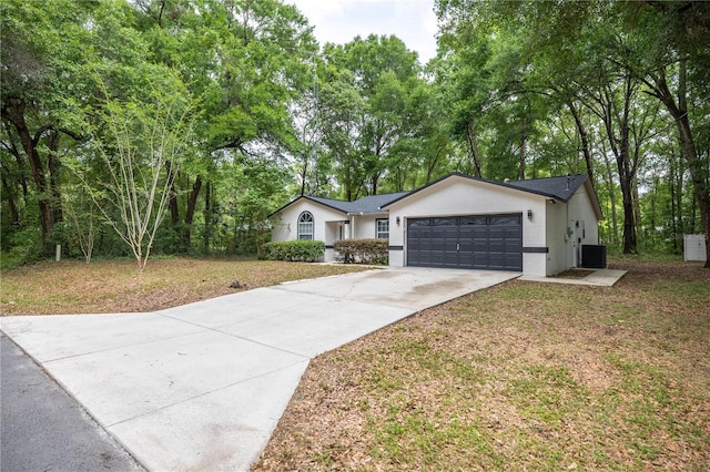 view of front of property featuring central AC unit, concrete driveway, a front yard, a garage, and stucco siding