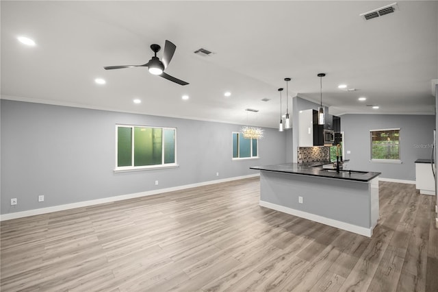 kitchen featuring dark countertops, crown molding, visible vents, and ceiling fan with notable chandelier