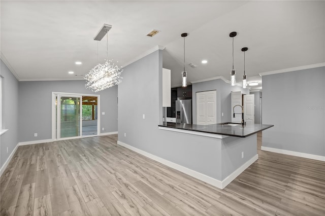 kitchen with stainless steel fridge, dark countertops, ornamental molding, and a sink