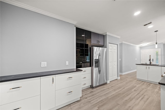 kitchen featuring backsplash, dark countertops, ornamental molding, a sink, and appliances with stainless steel finishes