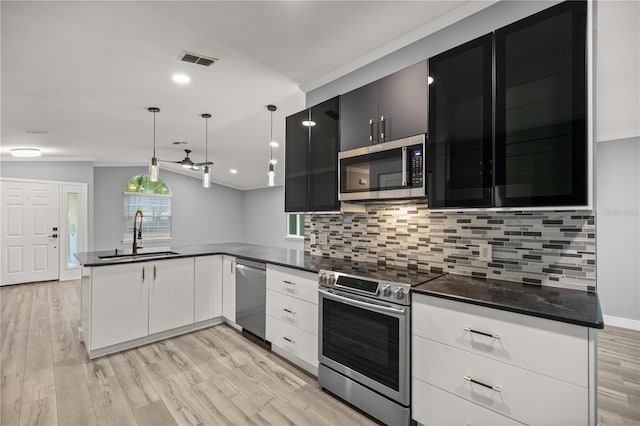 kitchen featuring a peninsula, a sink, dark countertops, visible vents, and appliances with stainless steel finishes