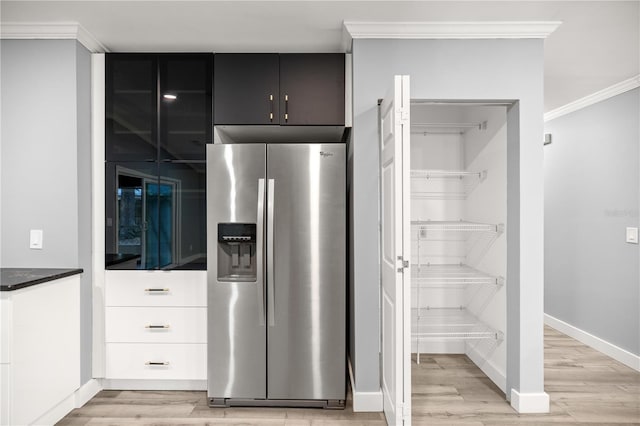 interior space featuring stainless steel fridge, light wood-style floors, crown molding, and baseboards