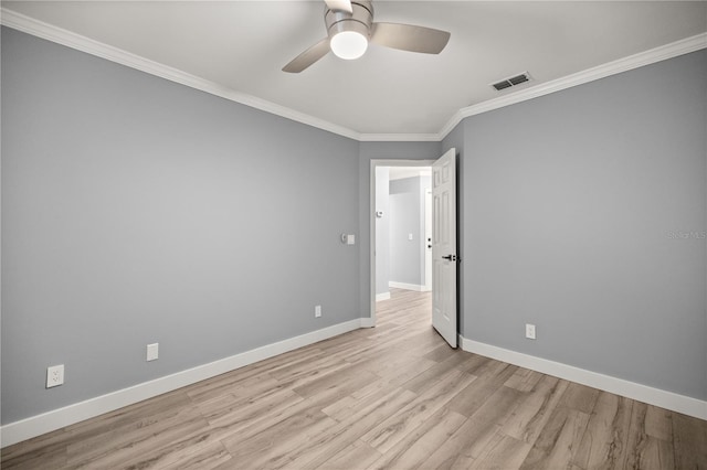 empty room featuring baseboards, crown molding, wood finished floors, and visible vents