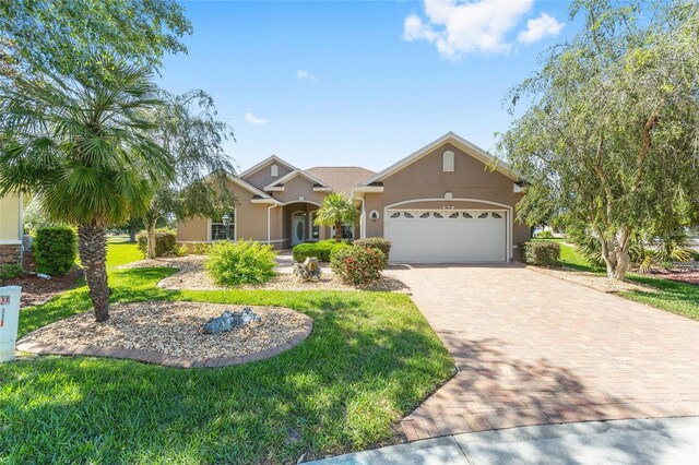8632 SW 86th Cir, Ocala, FL 34481 - view of front of property featuring a garage, stucco siding, decorative driveway, and a front yard