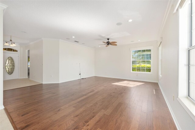 8632 SW 86th Cir, Ocala, FL 34481 - unfurnished living room with crown molding, baseboards, ceiling fan with notable chandelier, and wood finished floors