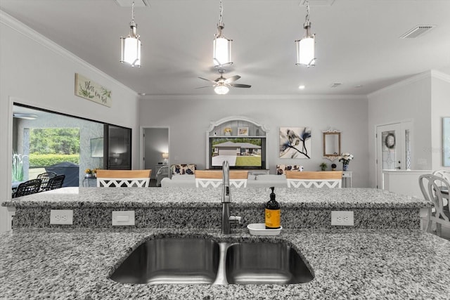 kitchen with ceiling fan, crown molding, light stone countertops, and a sink