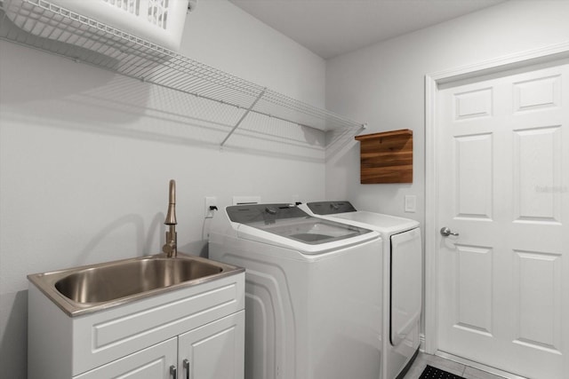 washroom featuring cabinet space, washing machine and clothes dryer, and a sink