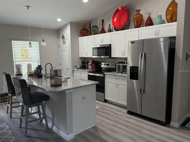 kitchen with white cabinetry, stainless steel appliances, light wood-style flooring, and a sink