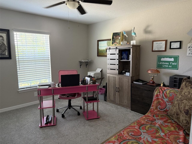 carpeted office space with baseboards, a healthy amount of sunlight, and ceiling fan