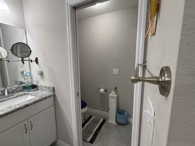 bathroom featuring vanity, toilet, a textured wall, and tile patterned floors