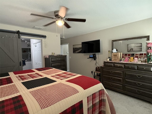 bedroom featuring light colored carpet, visible vents, a barn door, and ceiling fan