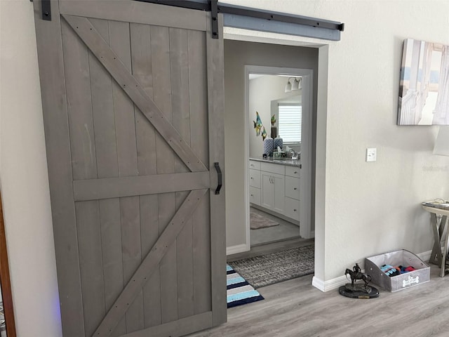 interior space with baseboards, a barn door, a sink, and wood finished floors