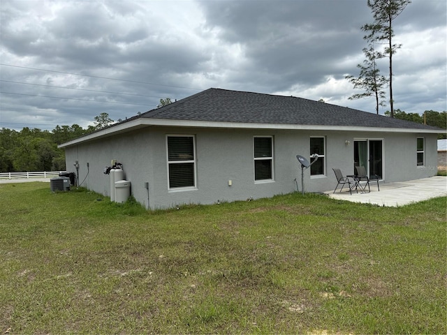 rear view of property featuring central AC, stucco siding, fence, a lawn, and a patio area