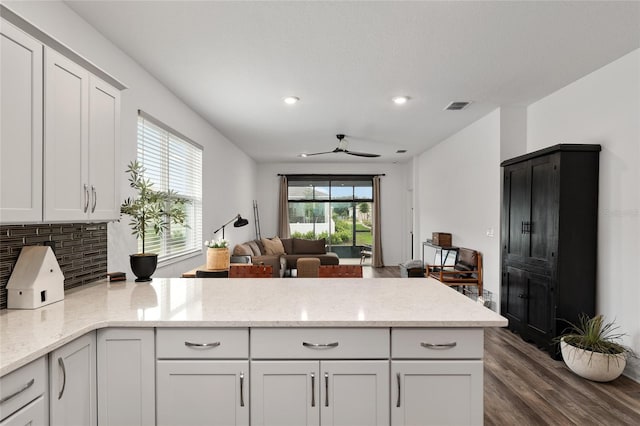 kitchen featuring visible vents, a ceiling fan, a peninsula, open floor plan, and dark wood-style flooring