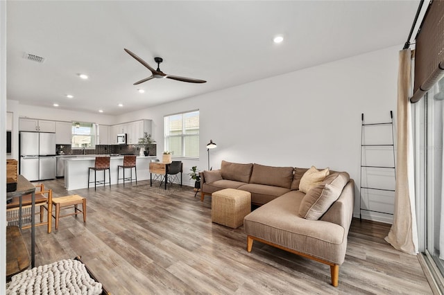 living room featuring recessed lighting, light wood-type flooring, visible vents, and a ceiling fan