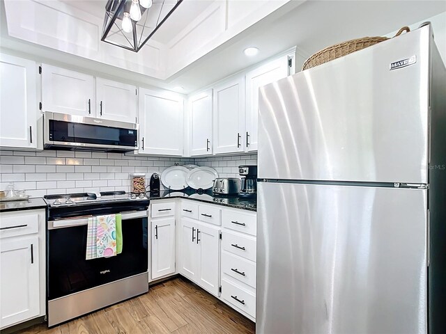 4806 SW County Road 769, Arcadia, FL 34269 - kitchen featuring dark countertops, appliances with stainless steel finishes, tasteful backsplash, wood finished floors, and white cabinets