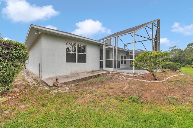 rear view of house with stucco siding, a patio area, a yard, and a lanai