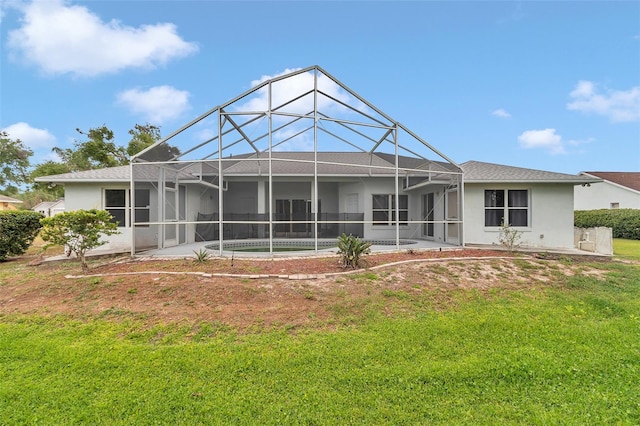 rear view of property with stucco siding, a lawn, and glass enclosure