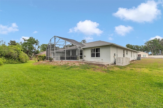 rear view of house with stucco siding, a yard, and a lanai