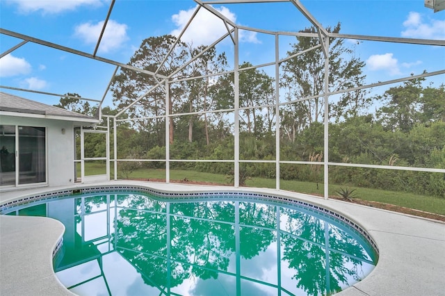 outdoor pool with a lanai, a patio area, and view of wooded area