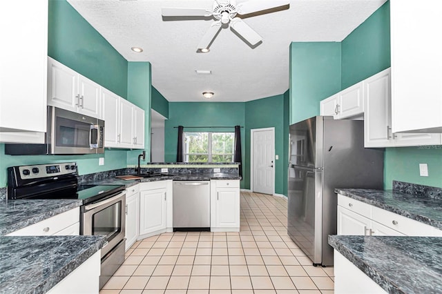 kitchen with stainless steel appliances, a peninsula, a sink, white cabinets, and ceiling fan