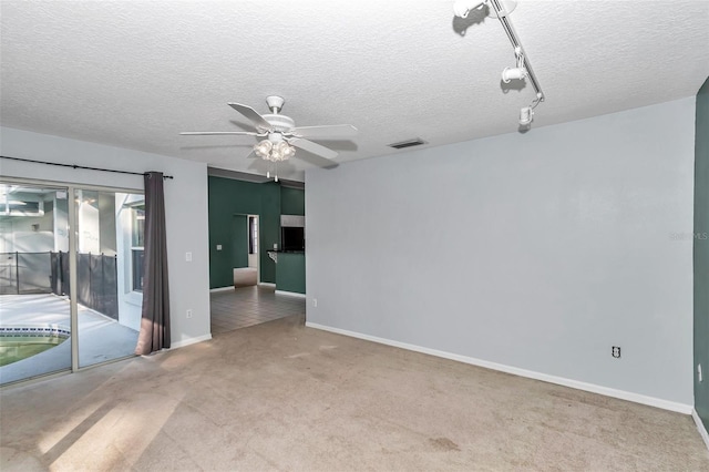 carpeted empty room featuring ceiling fan, a textured ceiling, and baseboards