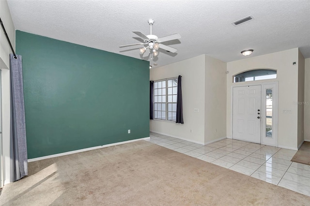 tiled foyer entrance featuring carpet floors, ceiling fan, a textured ceiling, and baseboards
